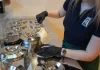 Pracowniczka nabiera lody z metalowych pojemników w profesjonalnej witrynie.