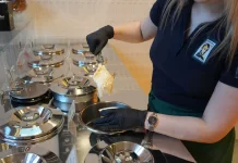 Jak wybrać odpowiedni sprzęt do produkcji lodów rzemieślniczych Pracowniczka nabiera lody z metalowych pojemników w profesjonalnej witrynie.