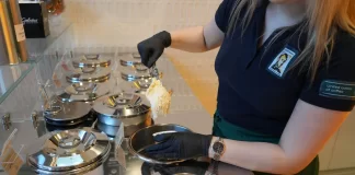 Pracowniczka nabiera lody z metalowych pojemników w profesjonalnej witrynie.