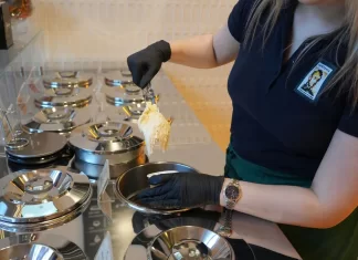Jak wybrać odpowiedni sprzęt do produkcji lodów rzemieślniczych Pracowniczka nabiera lody z metalowych pojemników w profesjonalnej witrynie.